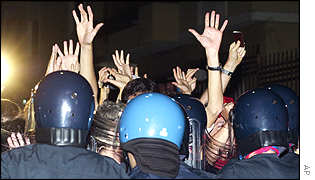 Protesters raise their hands in surrender as the police raid their centre